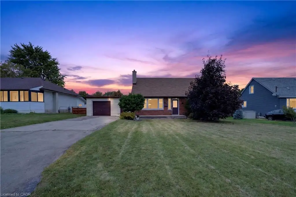 Expansive front lawn, paved driveway, attached single-car garage, brick and siding exterior, and a prominent front entrance