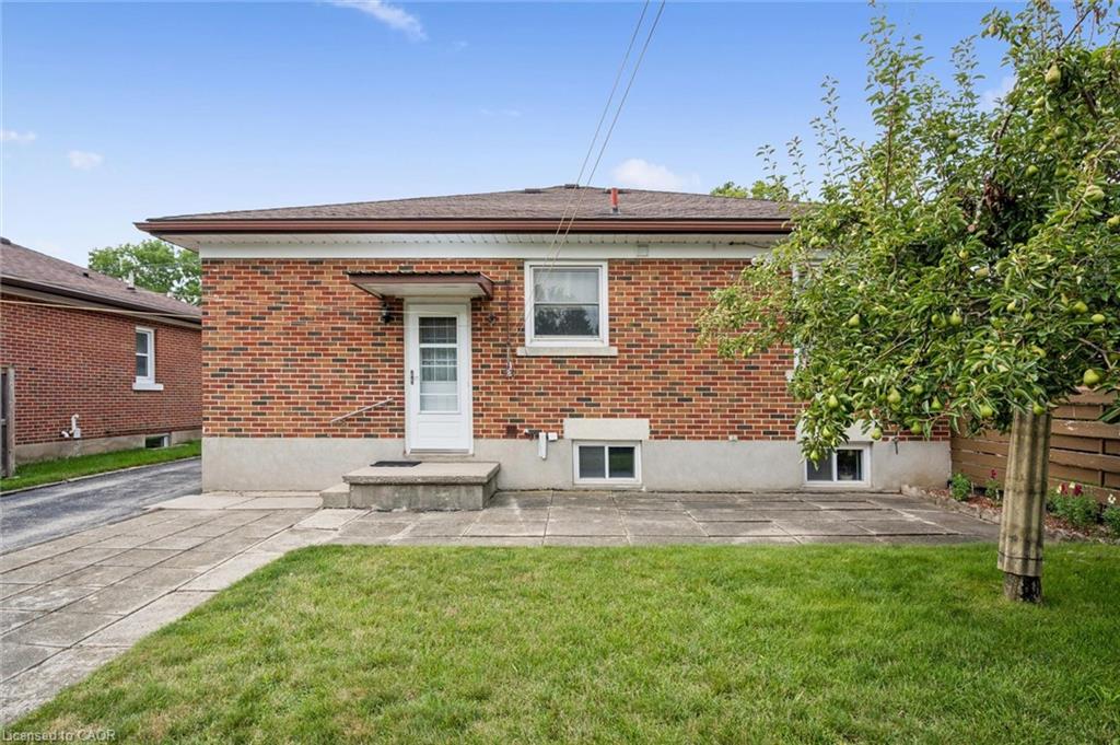 Brick exterior with a side entrance, concrete patio, and a mature fruit-bearing tree