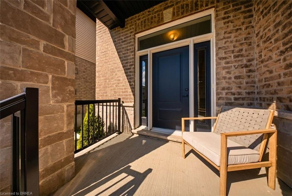 Covered porch entry featuring a dark paneled door with sidelight, overhead light fixture, brick facade, and stone accent wall