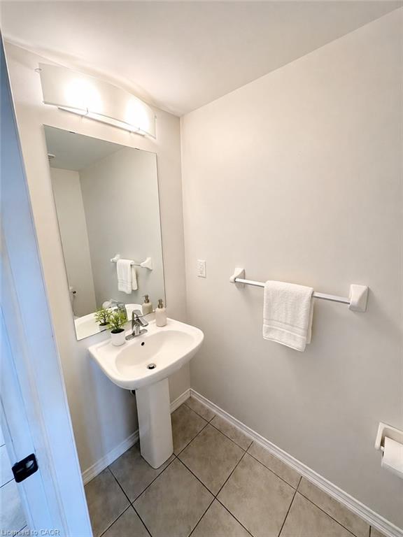 Pedestal sink with a single-handle faucet, rectangular mirror, and overhead vanity lighting