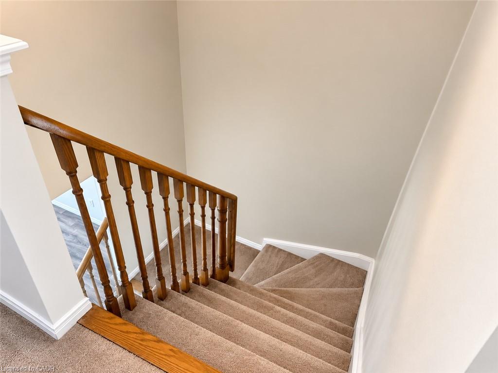 Carpeted staircase with wood railing and balusters
