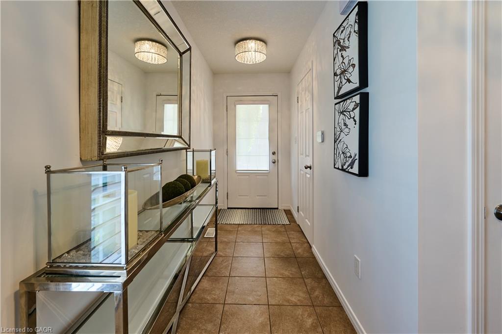Tiled flooring, white entry door with frosted glass panel, and two surface-mounted light fixtures