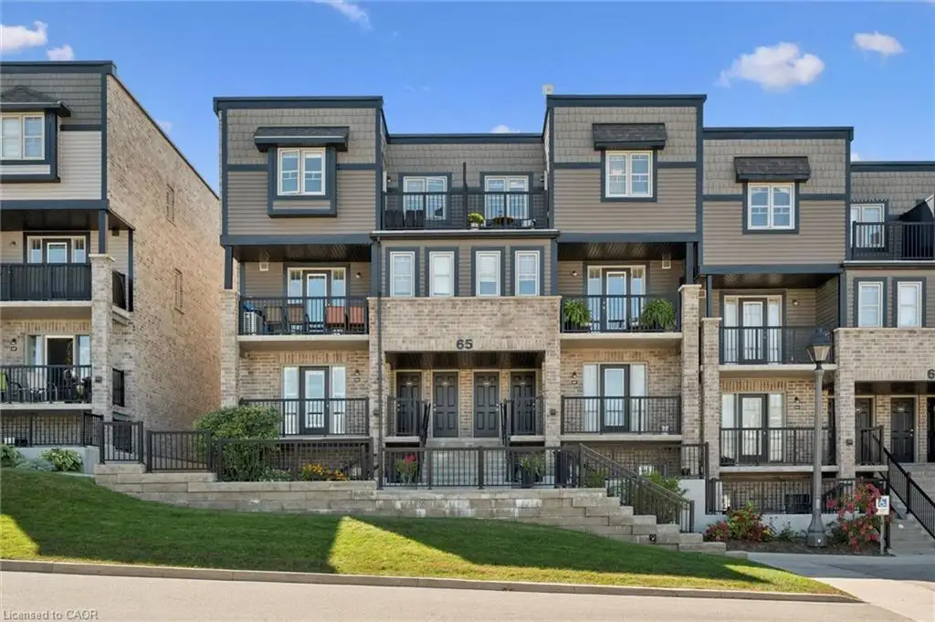 Contemporary townhome featuring brick and siding exterior, multiple balconies with black railings, and a tiered landscaped front