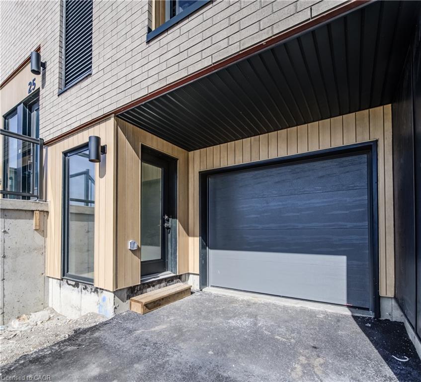 Exterior with light brick siding and wood-finish paneling, featuring a dark overhead garage door, a black framed entry door, and exterior wall sconces