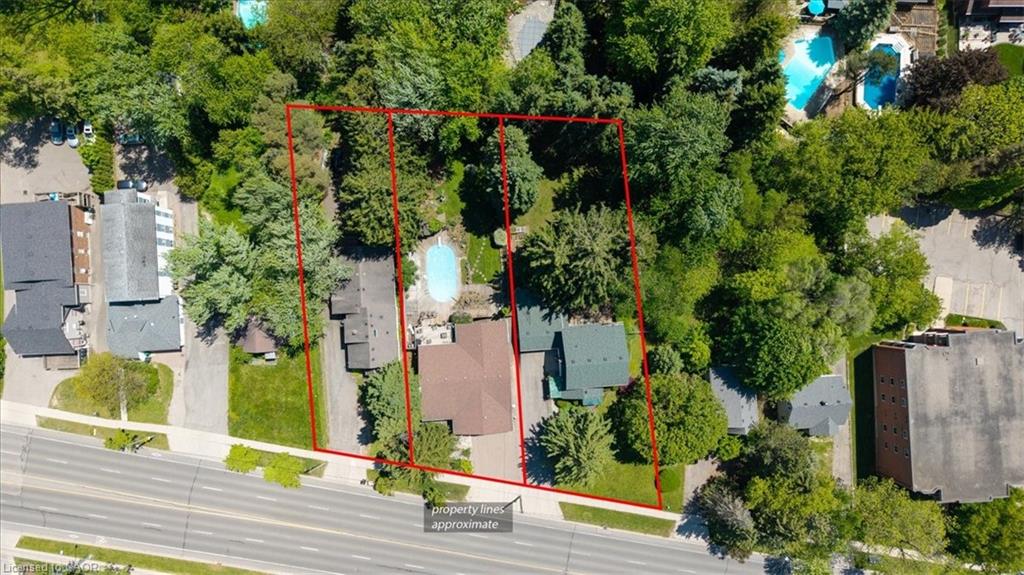 Aerial view of a residential property featuring extensive tree coverage, a brown-roofed structure, and a visible swimming pool