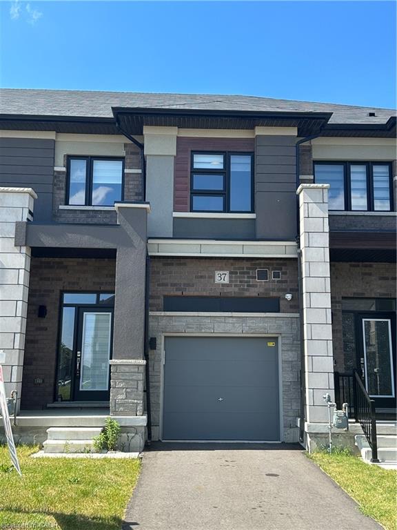 Contemporary townhouse exterior featuring a dark gray garage door, brick and stone facade, contrasting siding, and black-framed windows