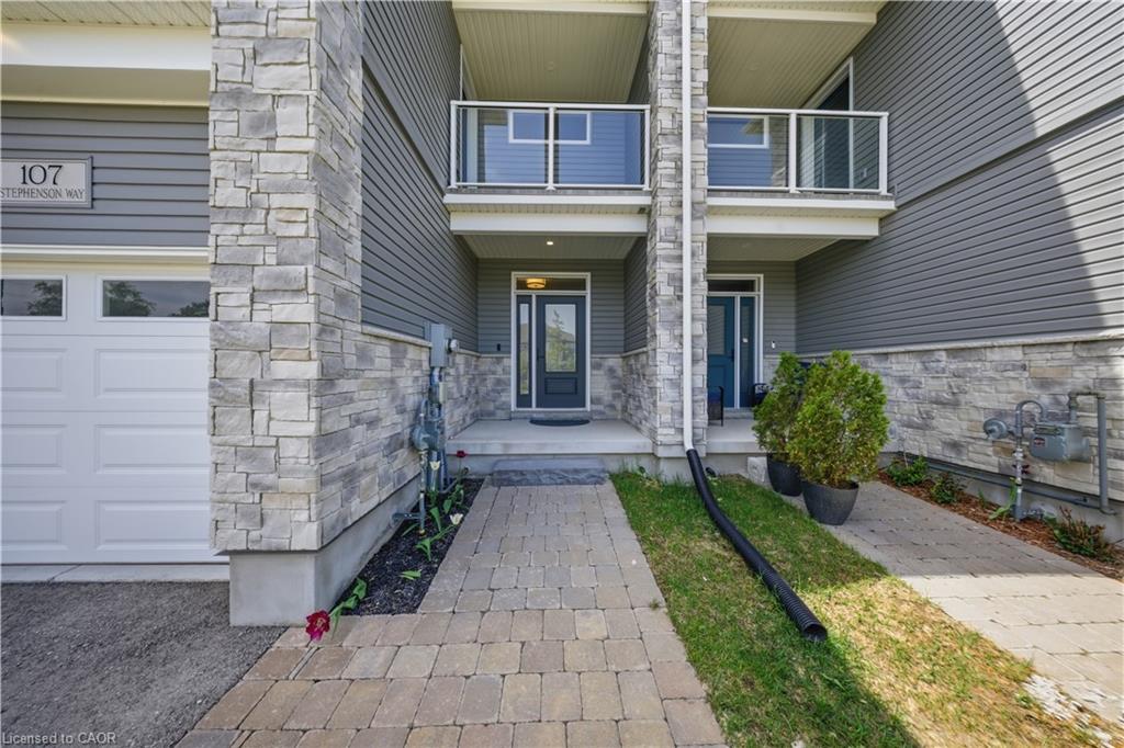 Stone and siding exterior with a garage door and paved walkway