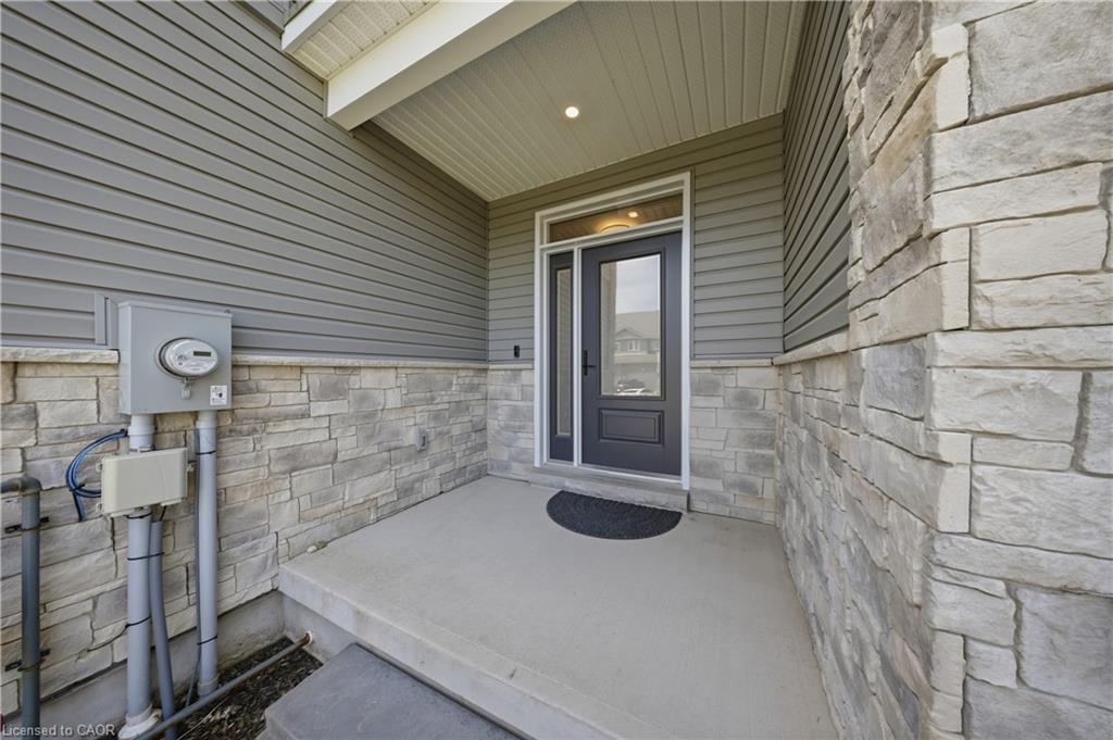Inviting front entry featuring a concrete porch, dark gray entry door with partial glass, integrated sidelight, and an overhead porch light