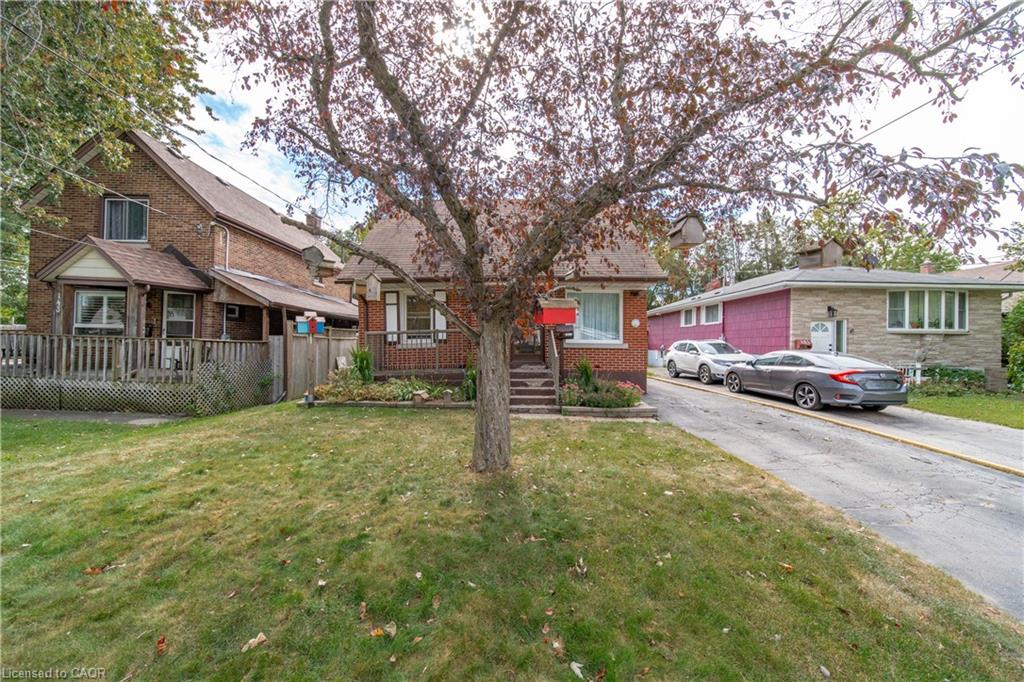 Front yard with mature tree, asphalt driveway, and front porch