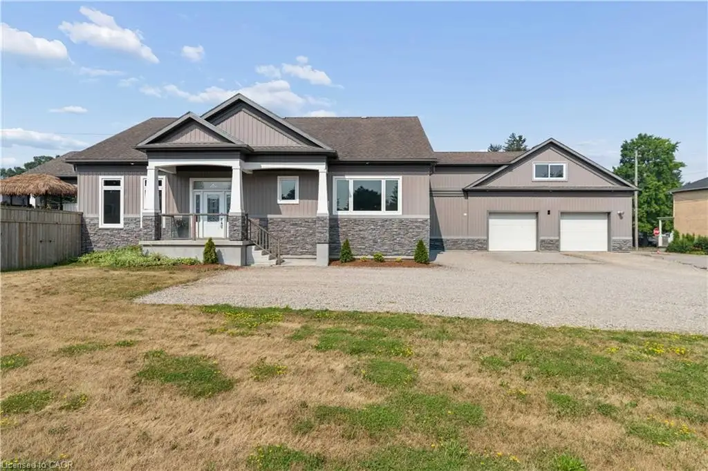 Modern bungalow exterior featuring a covered entry, stone facade accents, light gray siding, and a two-car garage with overhead storage