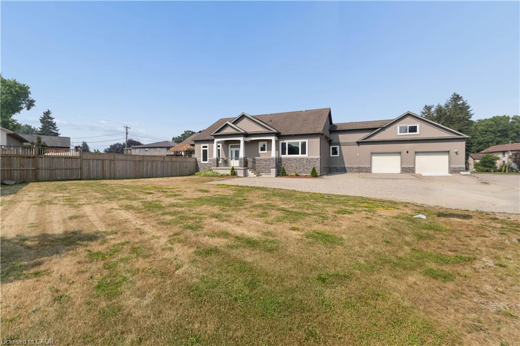 Contemporary residence featuring a spacious two-car garage, stone and siding exterior, a covered front entry, and a large fenced yard