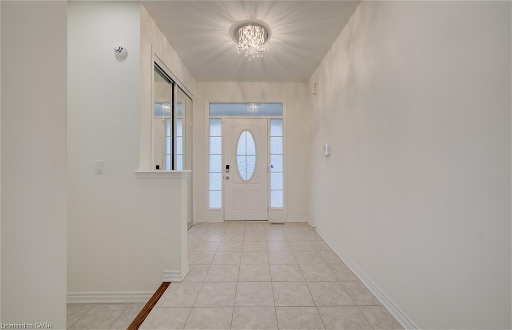 Entryway featuring a white door with oval glass insert, frosted sidelights, a transom window, and a decorative ceiling fixture