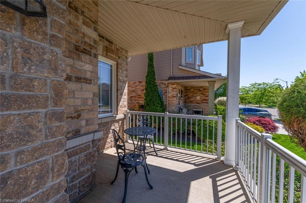 Covered front porch featuring a stone and brick facade, white column, and white railings