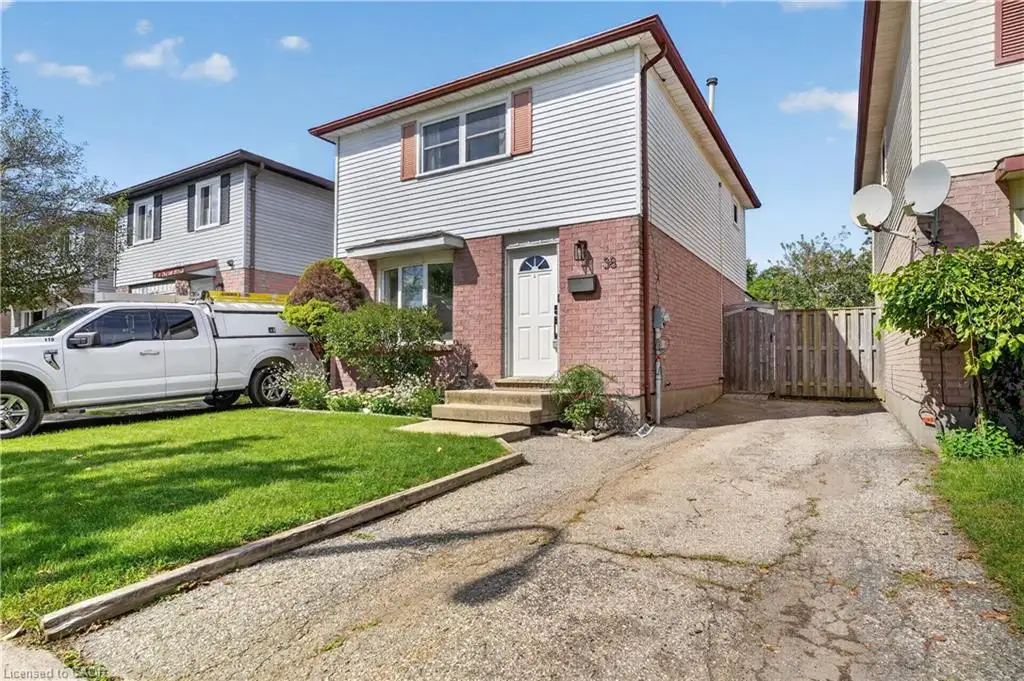 Two-story residence featuring a brick and siding exterior, front yard with mature landscaping, and a side driveway leading to a wooden fence