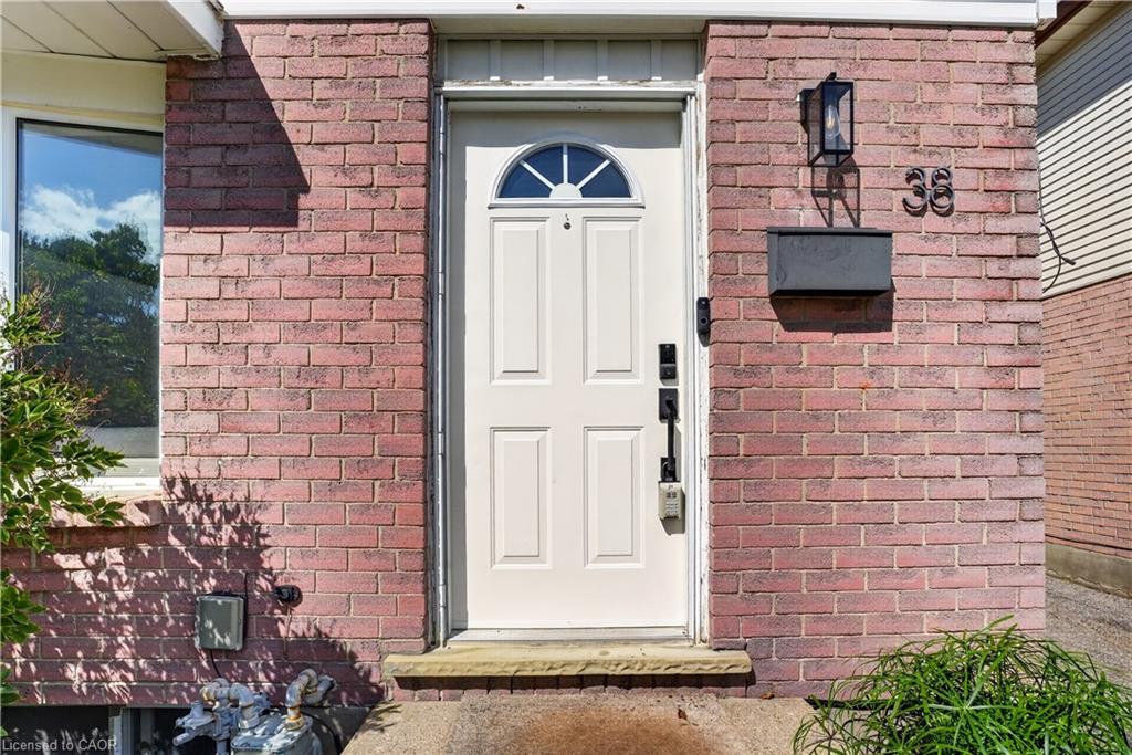 Red brick exterior with white paneled door, arched transom window, and a black wall-mounted lantern