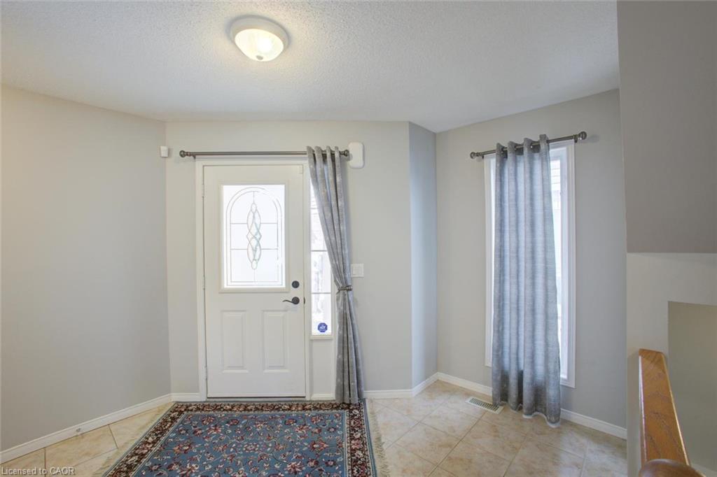 Entryway featuring a white door with decorative glass insert, a transom window, and tiled flooring