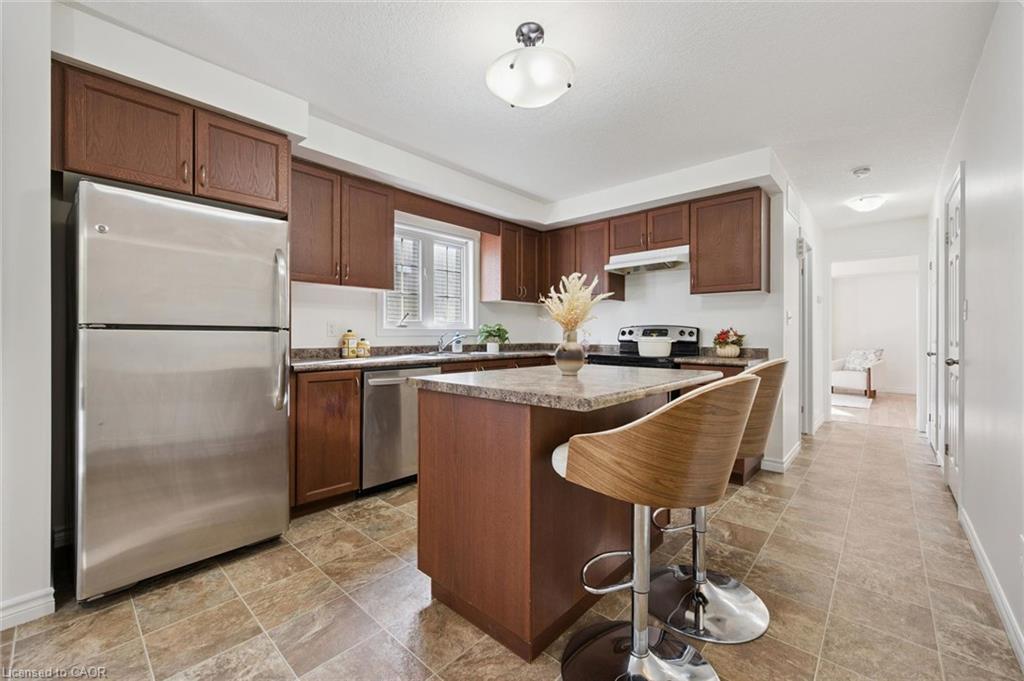 Full kitchen featuring wood-finish cabinetry, stainless steel appliances, stone-finish countertops, and a kitchen island with seating