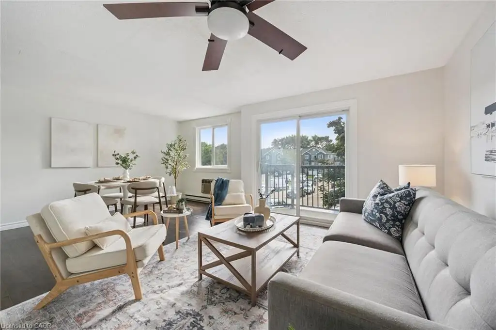 Open-concept living area with dark wood-finish flooring, white walls, a ceiling fan, and a sliding glass door leading to a balcony