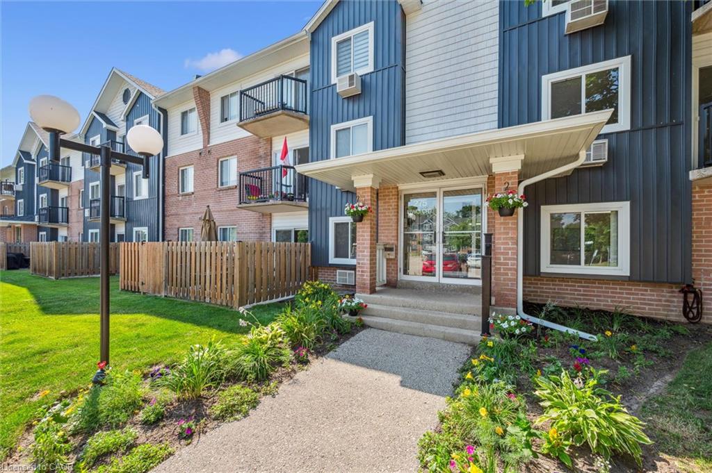 Welcoming entry with concrete steps and an awning, surrounded by a landscaped garden bed