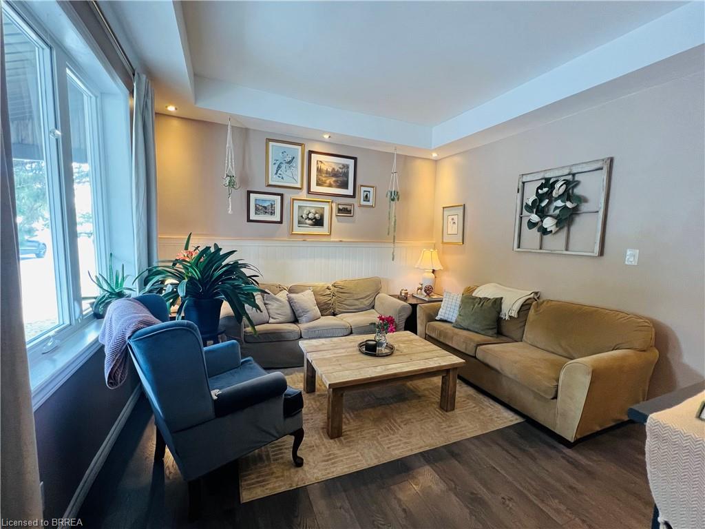 Wood-finish flooring, recessed ceiling lighting, tray ceiling, and a large bay window