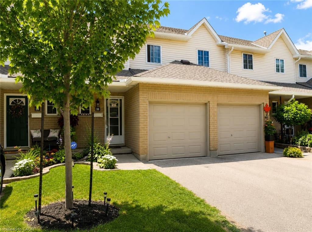 Brick and siding exterior featuring a two-car garage, front entry porch, and landscaped garden beds