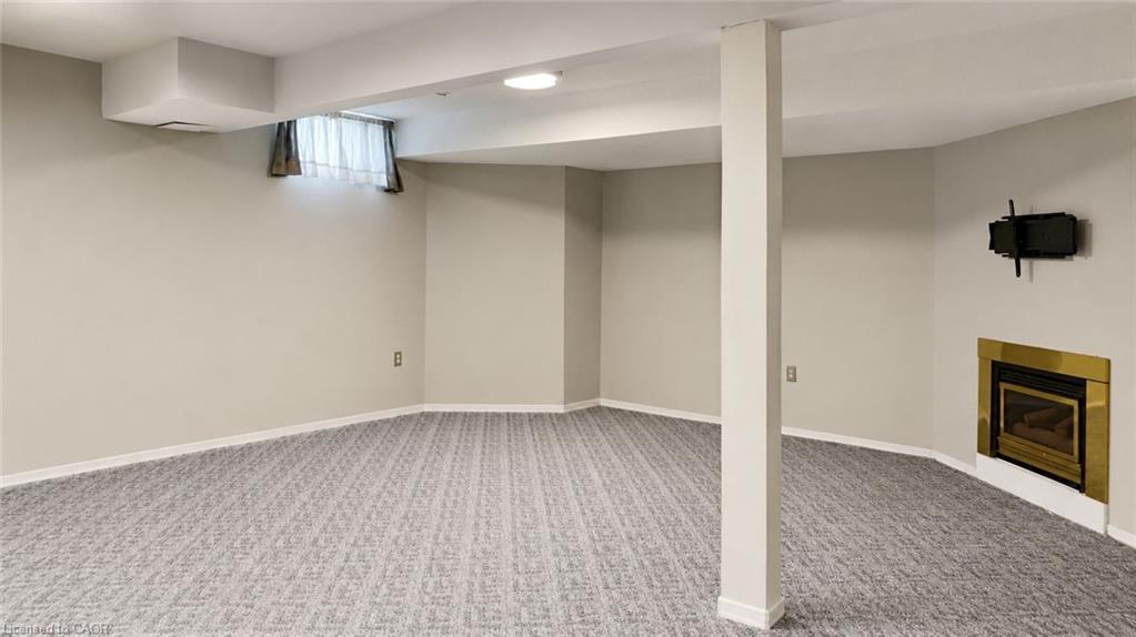 Wall-to-wall patterned carpet, light gray walls, recessed lighting, and a built-in fireplace with a brass trim