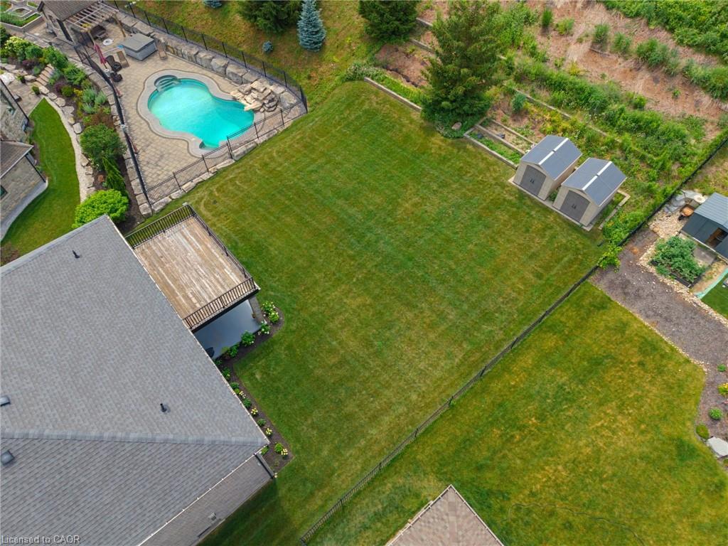 Expansive rear yard featuring a freeform swimming pool with rock features, a paved patio, a wooden deck, and two storage sheds