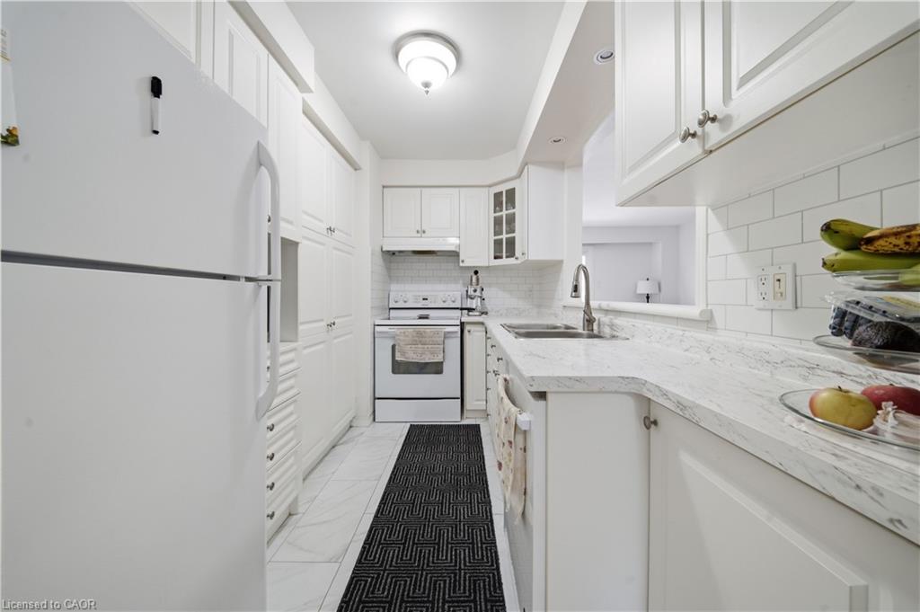 Kitchen featuring white cabinetry, white subway tile backsplash, light-colored countertops, and stainless steel sink