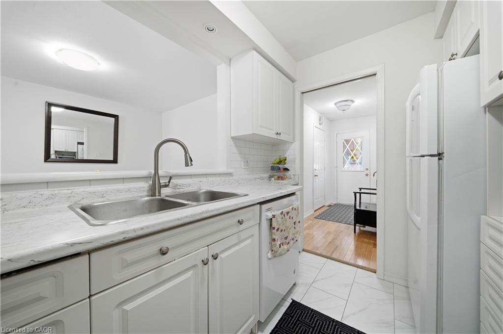 Kitchen featuring white cabinetry, a double basin stainless steel sink, a pull-down faucet, and white countertops
