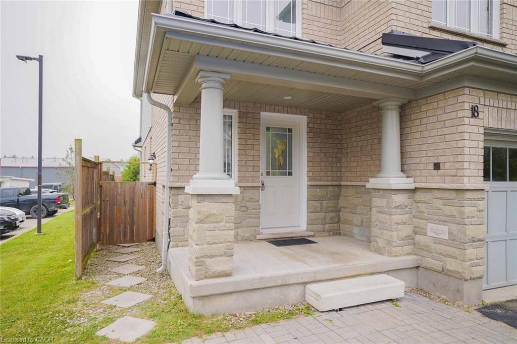 Brick facade with stone accents, covered front porch, decorative entry door, and a paver driveway