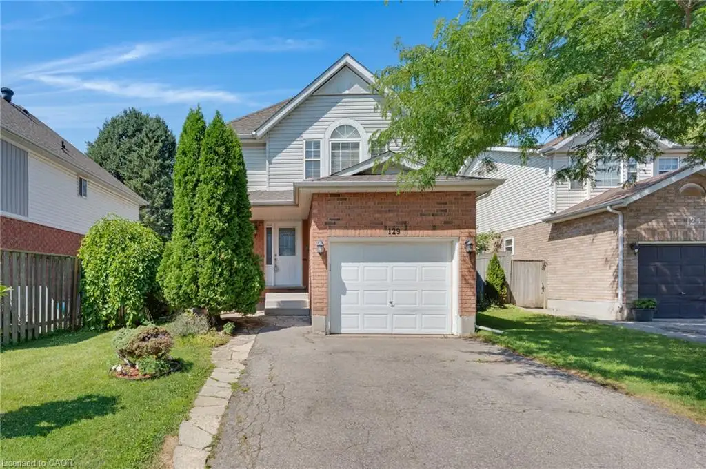 Two-story residence featuring a brick and siding exterior, an integrated garage with a white panel door, a paved driveway, and a stone walkway