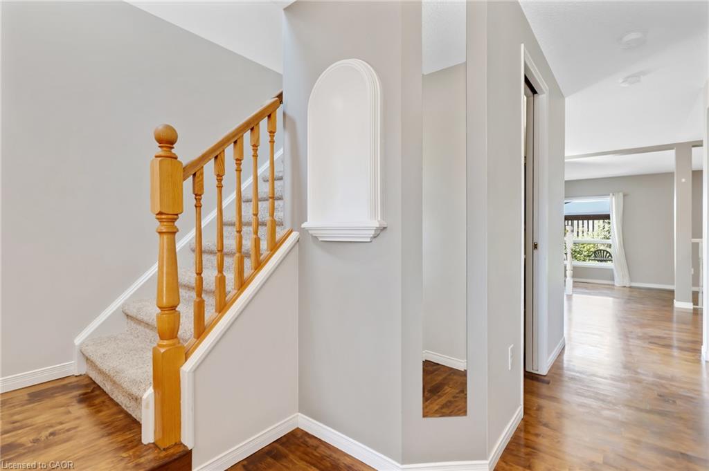 Carpeted staircase with wood banister, wood-finish flooring, and light gray wall paint