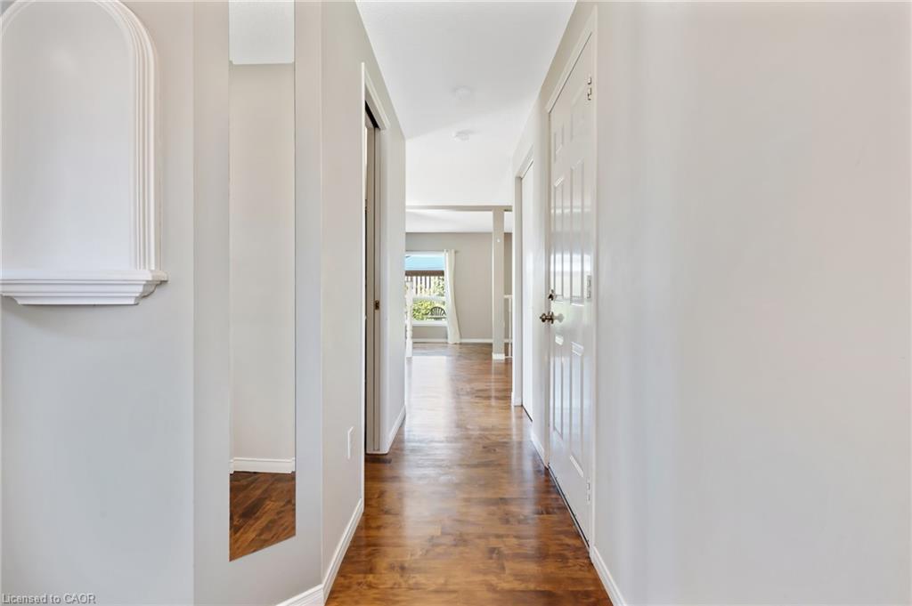Hallway featuring wood-finish flooring, light grey painted walls, recessed lighting, and a decorative wall niche with a shelf