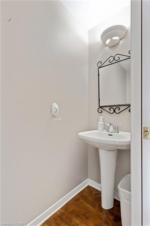 Pedestal sink with chrome faucet, complemented by wood-finish flooring and white baseboards