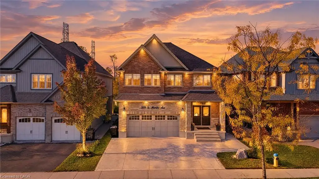 Multi-story residence featuring a brick and stone facade, double-door entryway, attached two-car garage, and concrete driveway