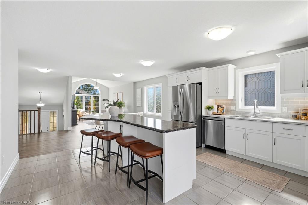 Kitchen featuring a large island with seating, stainless steel appliances, white cabinetry, and light subway tile backsplash