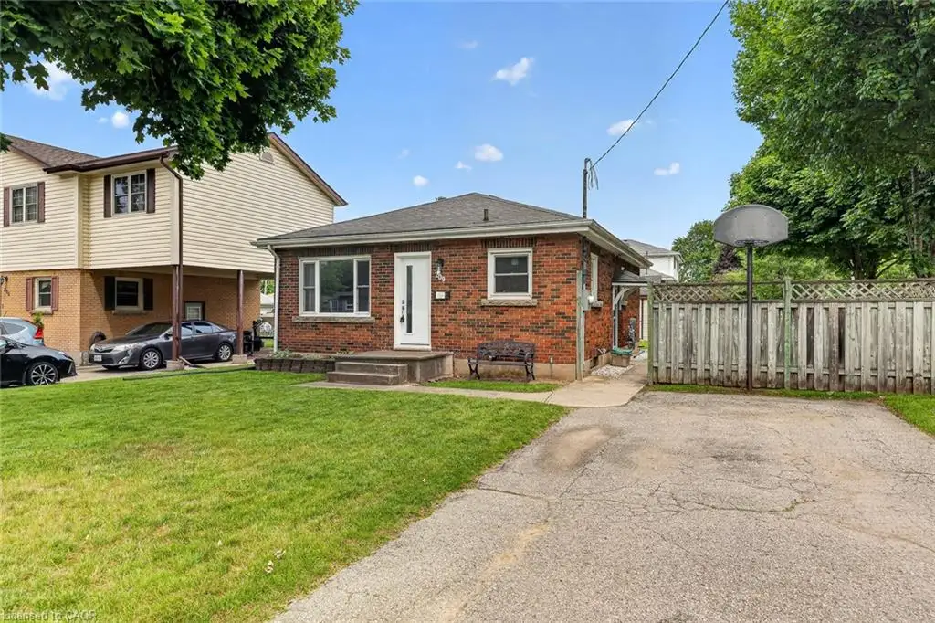 Brick-faced single-story residence featuring a front lawn and a paved driveway