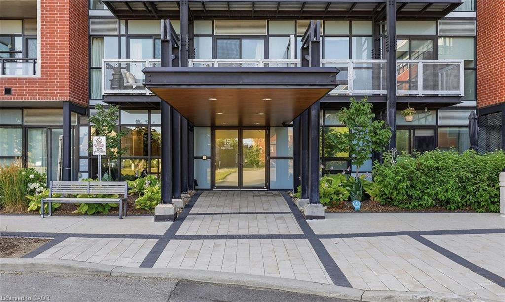 Entryway featuring a large overhang, glass double doors, brick detailing, and a paver walkway