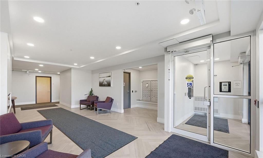 Building entrance with automatic glass doors, light wood-finish flooring, recessed ceiling lighting, and a mailroom