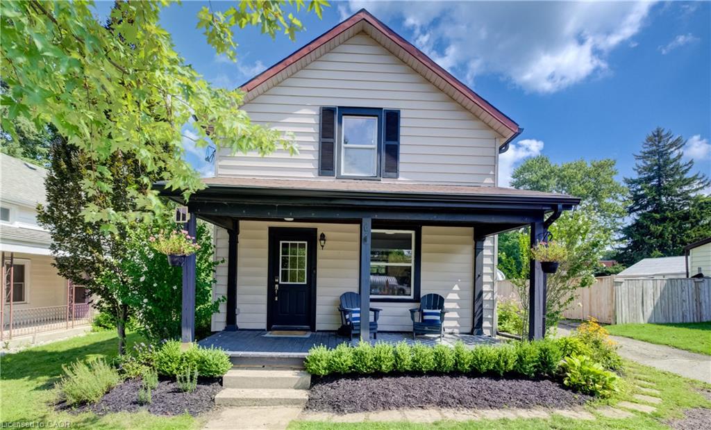 Two-story exterior with light-colored siding, covered front porch, and black window shutters