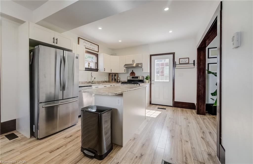Kitchen featuring light wood-finish flooring, white cabinetry, stainless steel appliances, and a central island with a light-toned countertop