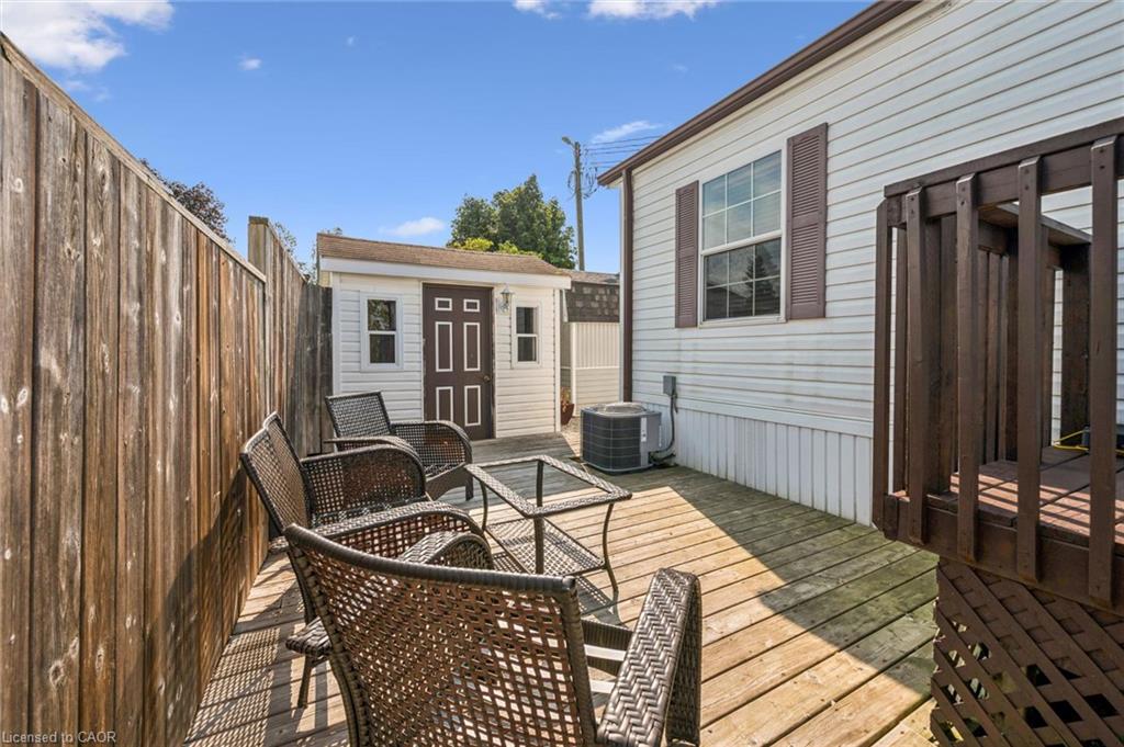Outdoor deck space featuring wood decking, a privacy fence, an exterior storage shed, and a side window with shutters