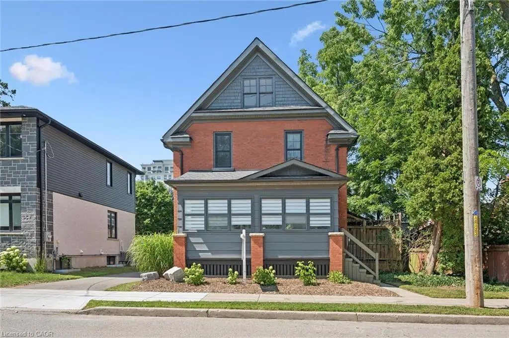 Two-story brick exterior featuring a gable roof, decorative shingle siding, and an enclosed front porch with painted wood paneling and brick pillars