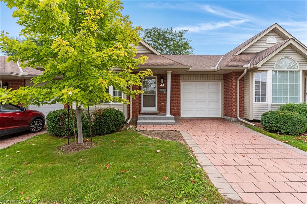 Brick and siding exterior with a shingled roof, featuring a paver driveway, an attached garage, and a bay window with an arched transom
