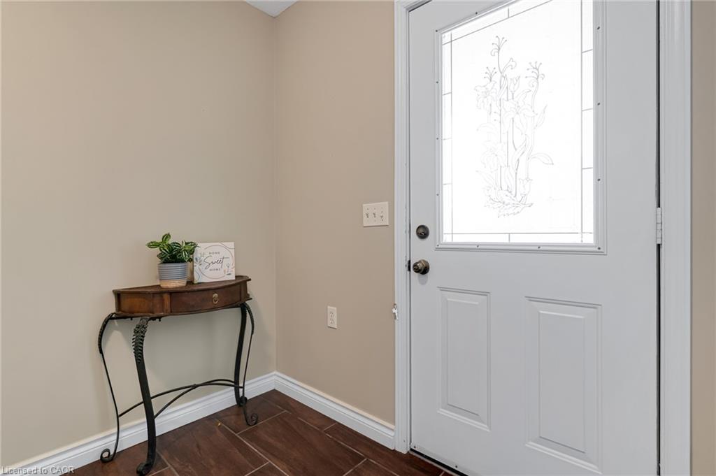 White paneled door with decorative glass inlay, wood-finish flooring, and neutral wall tones