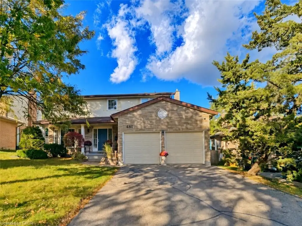 Two-story exterior featuring a stone facade, double-car garage, covered entryway, and mature landscaping