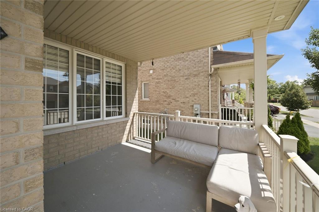 Covered front porch featuring a light brick exterior and white railing