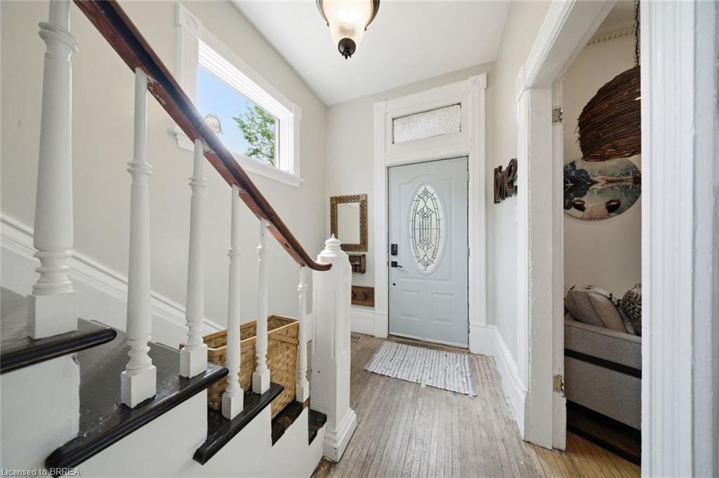 Entryway featuring wood-finish flooring, a light blue door with an oval leaded glass insert, and a transom window