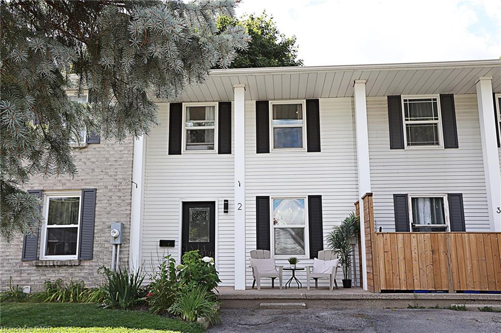 White vinyl siding exterior with black shutters, a covered front entrance, and a wood privacy screen