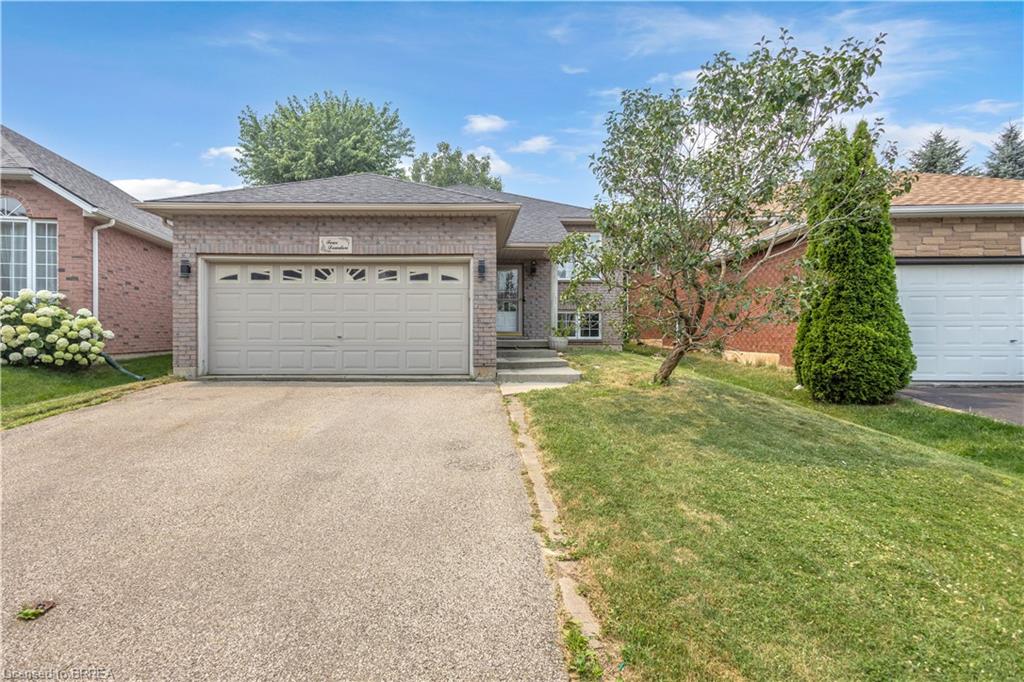 Brick exterior residence featuring an attached garage with decorative windows and an exposed aggregate driveway